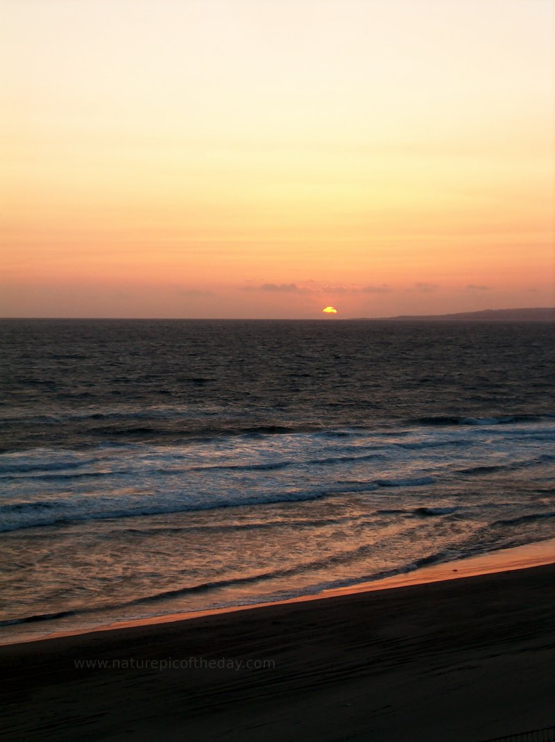 Picture of sun setting over the Pacific Ocean from a beach.